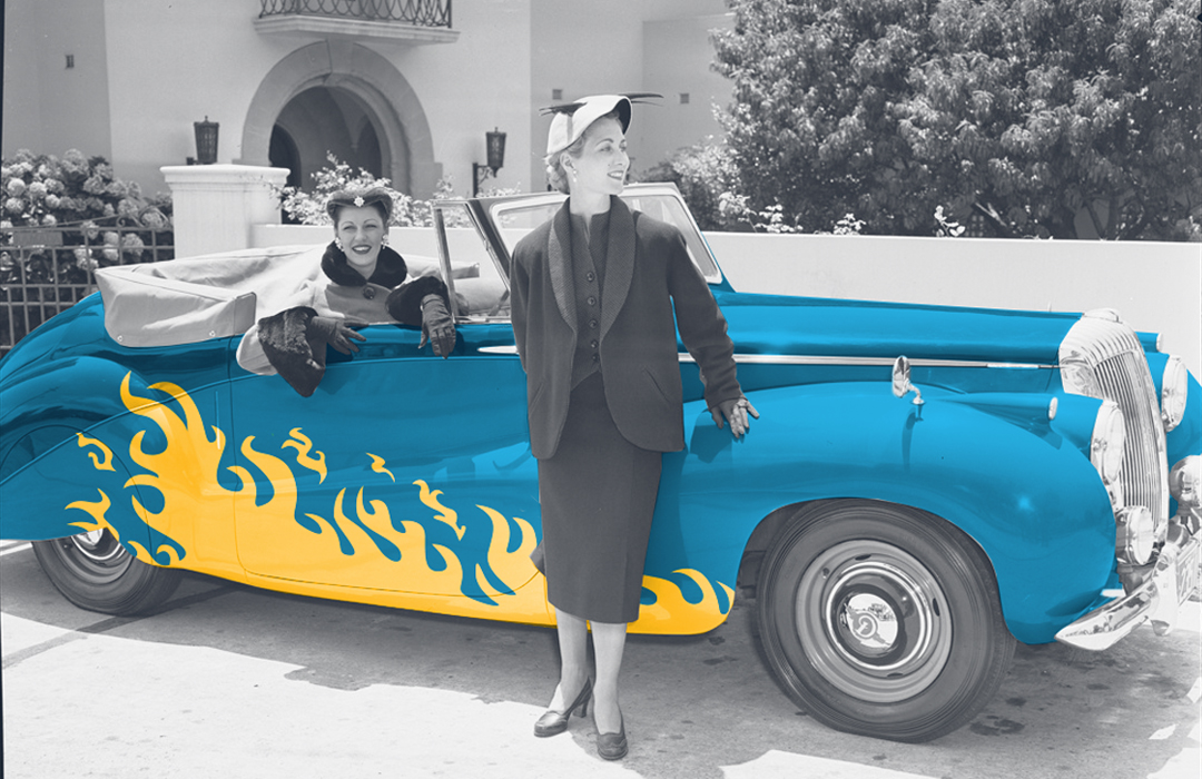 Two women pose with a classic car with flames on the sides, representing driving your business forward with digital marketing.