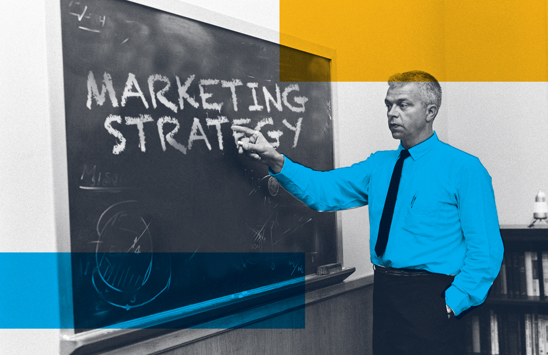 man points to words marketing strategy on chalkboard